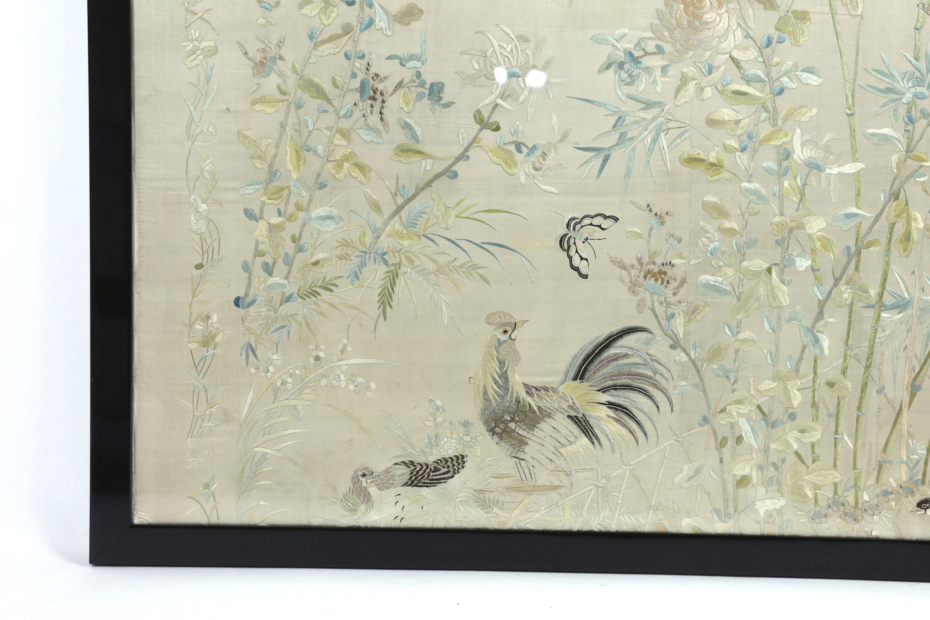 A framed early 20th century Chinese silk embroidered shawl, embroidered with chickens, ducks, flying birds and insects amongst bamboo and flowering plants, 126cm wide x 10.5cm high